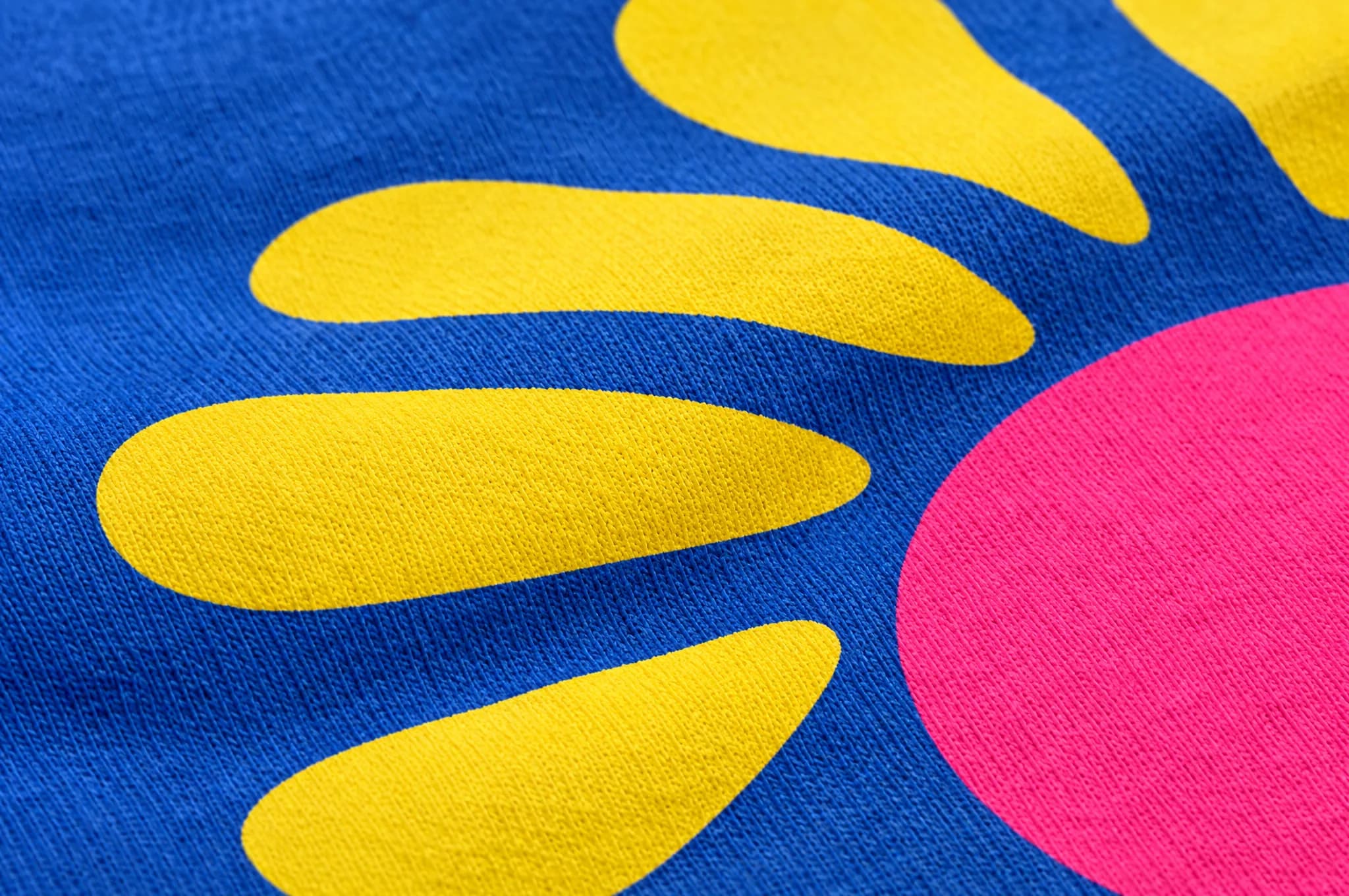Close-up of a yellow and pink screen print on a royal blue t-shirt