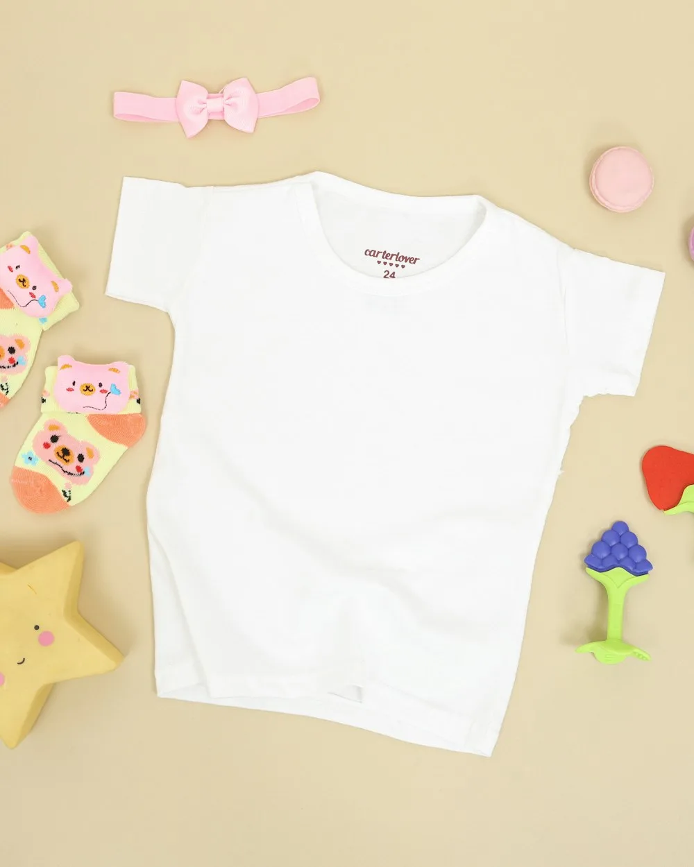 A blank white kids' t-shirt laid flat with baby socks and toys, ready to be custom printed