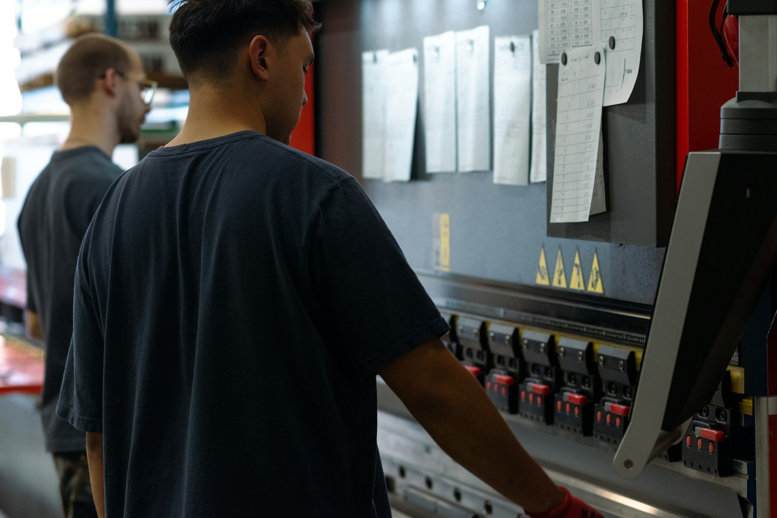 Two print shop staff standing at a work table checking a stack of freshly printed garments together