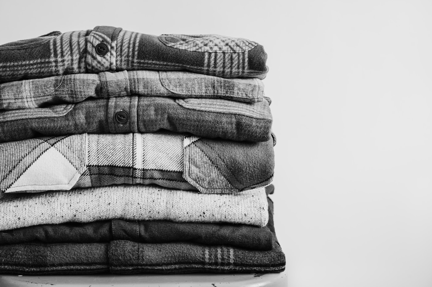 Folded cotton t-shirts beside raw cotton bolls