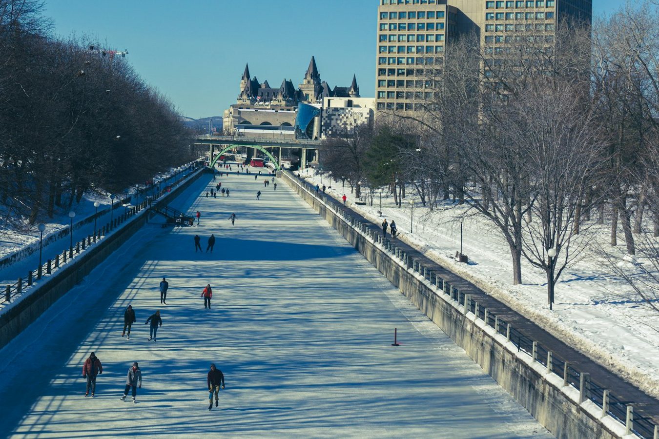 Skaters on the frozen Rideau Canal Skateway in downtown Ottawa, the Château Laurier at the far end and office towers along the bank
