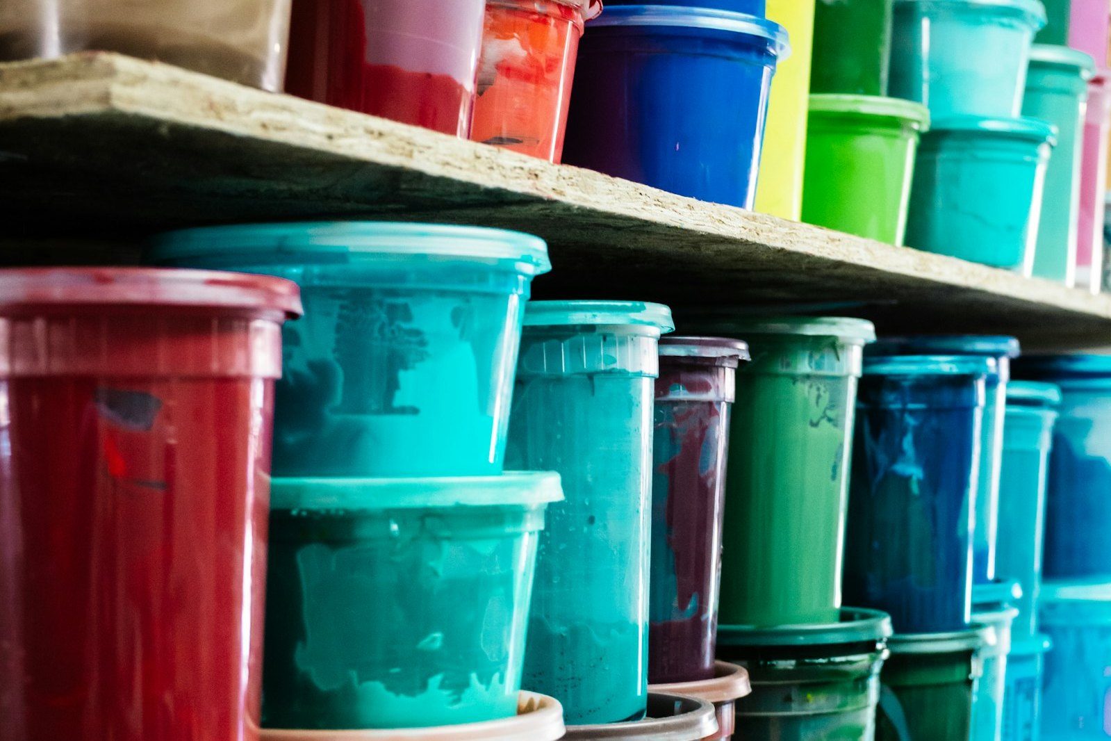 Shelves of screen-printing ink tubs in red, teal, green, purple and blue
