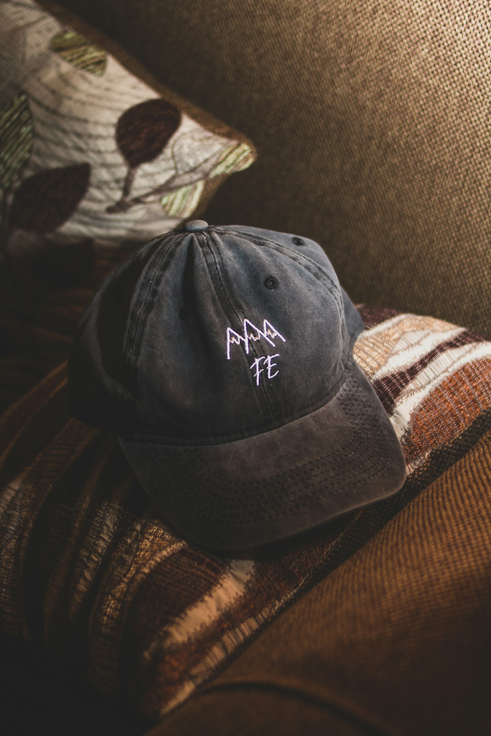 A dark structured cap with embroidered lettering resting on a textured surface
