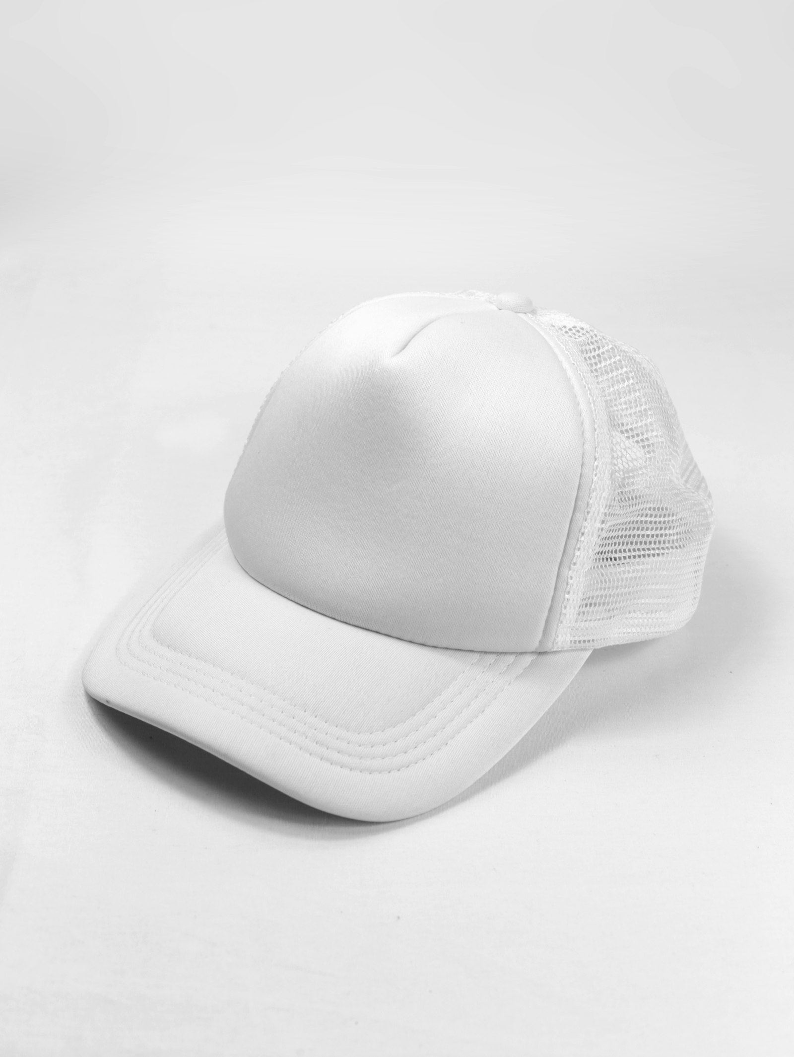 A plain white mesh-back trucker cap on a white background