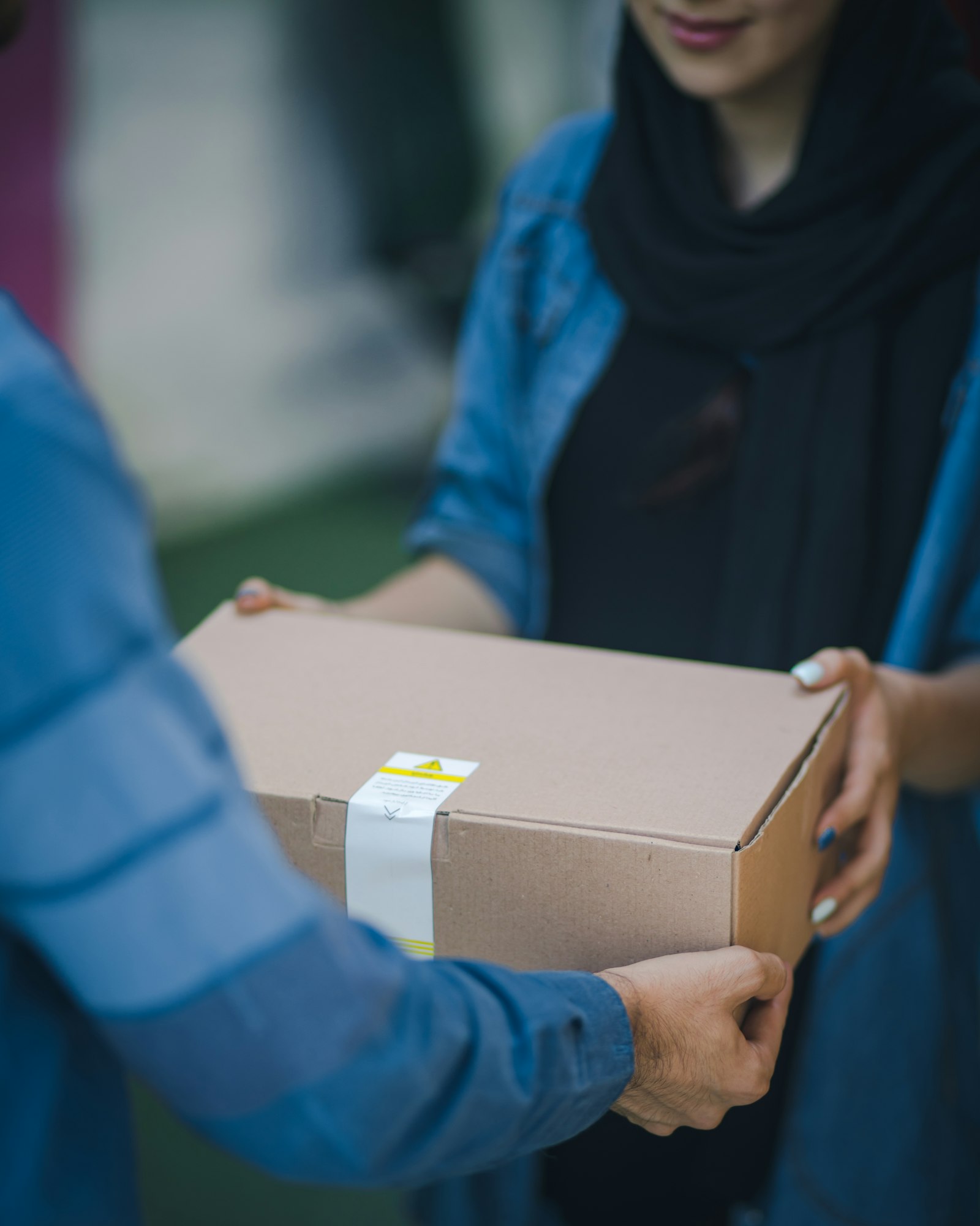 A sealed parcel being handed from one person to another