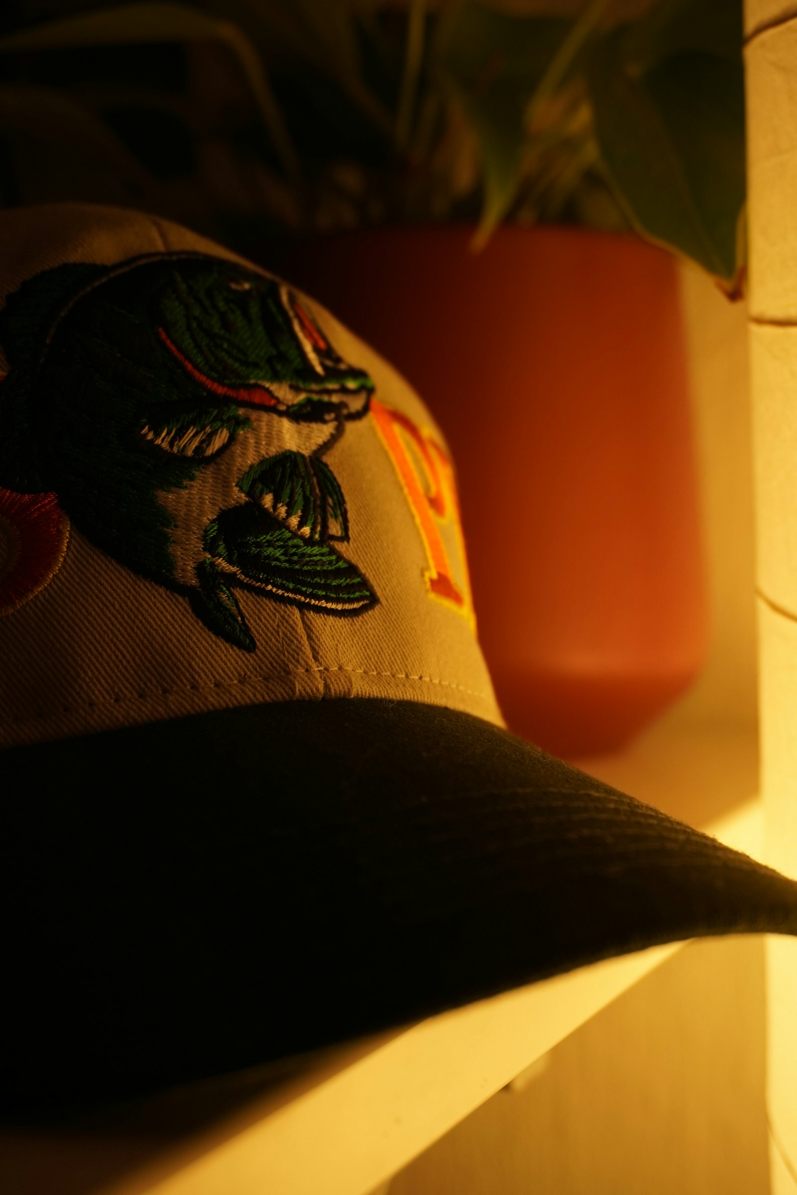 Close detail of dense coloured embroidery stitched across the front panel of a dark cap