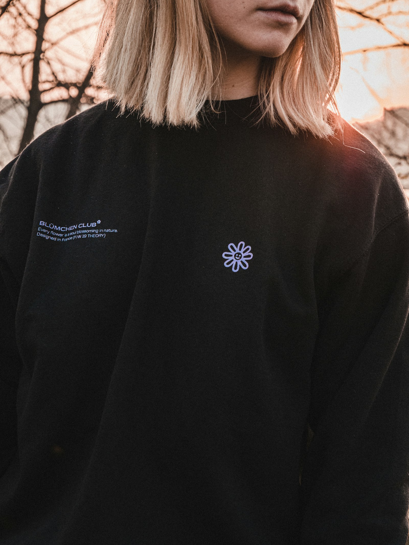 A person wearing a black sweatshirt with a small printed motif on the chest