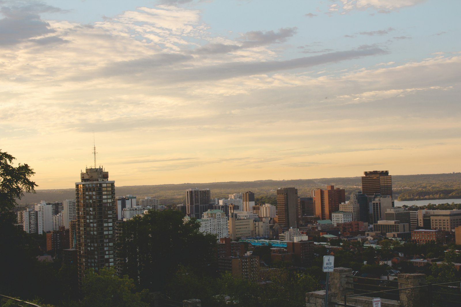 Downtown high-rises seen from the escarpment at dusk, with the lake and the sky glowing behind them