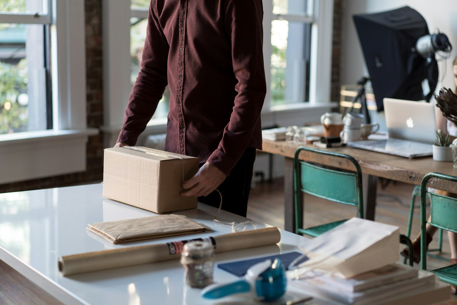 A person opening a cardboard parcel on a desk