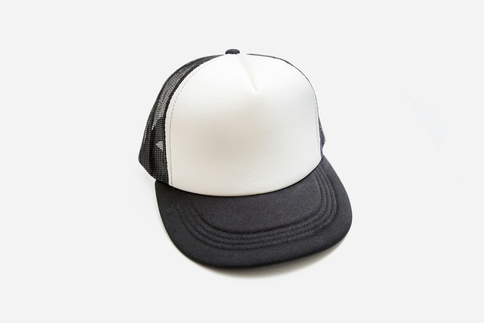 A white and black foam-front trucker cap photographed flat against a plain background