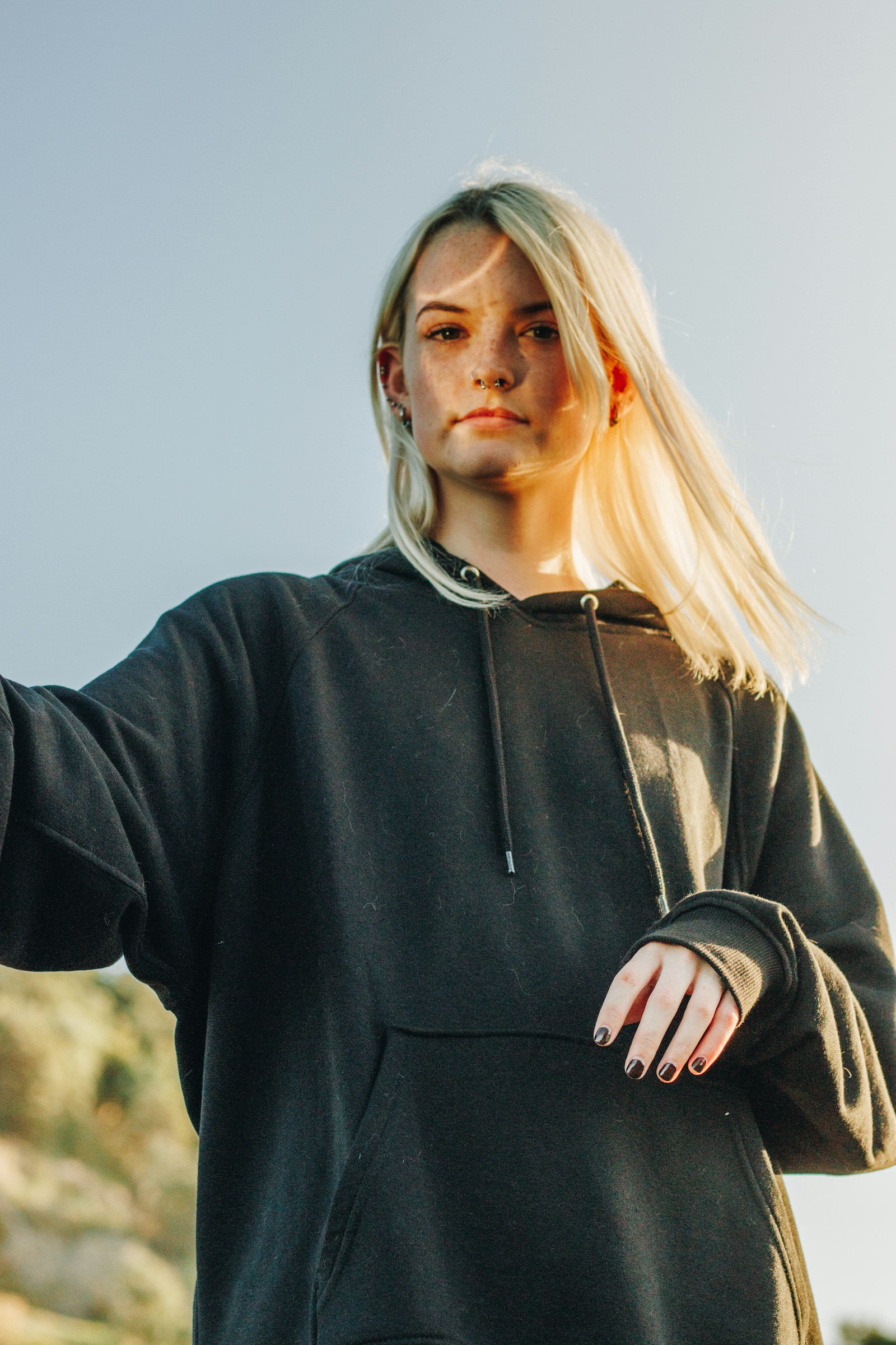A person wearing an oversized dark hoodie outdoors in low sun