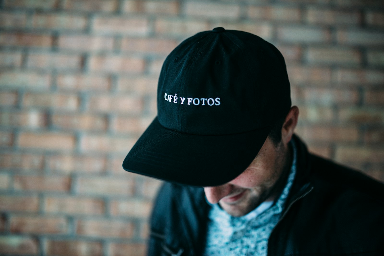 A man in a dark navy cap with small white embroidered text across the front panel