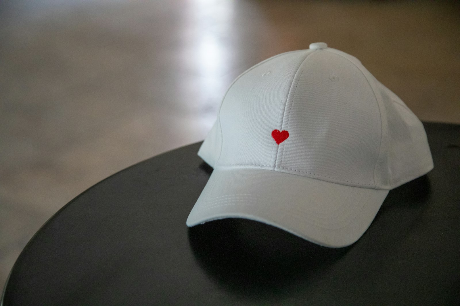 A white cap with a single small embroidered red heart on the front panel