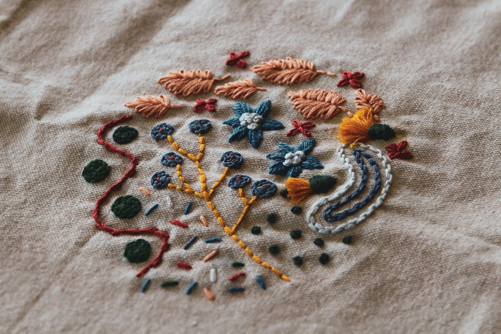 Close detail of coloured embroidery stitched into pale fabric