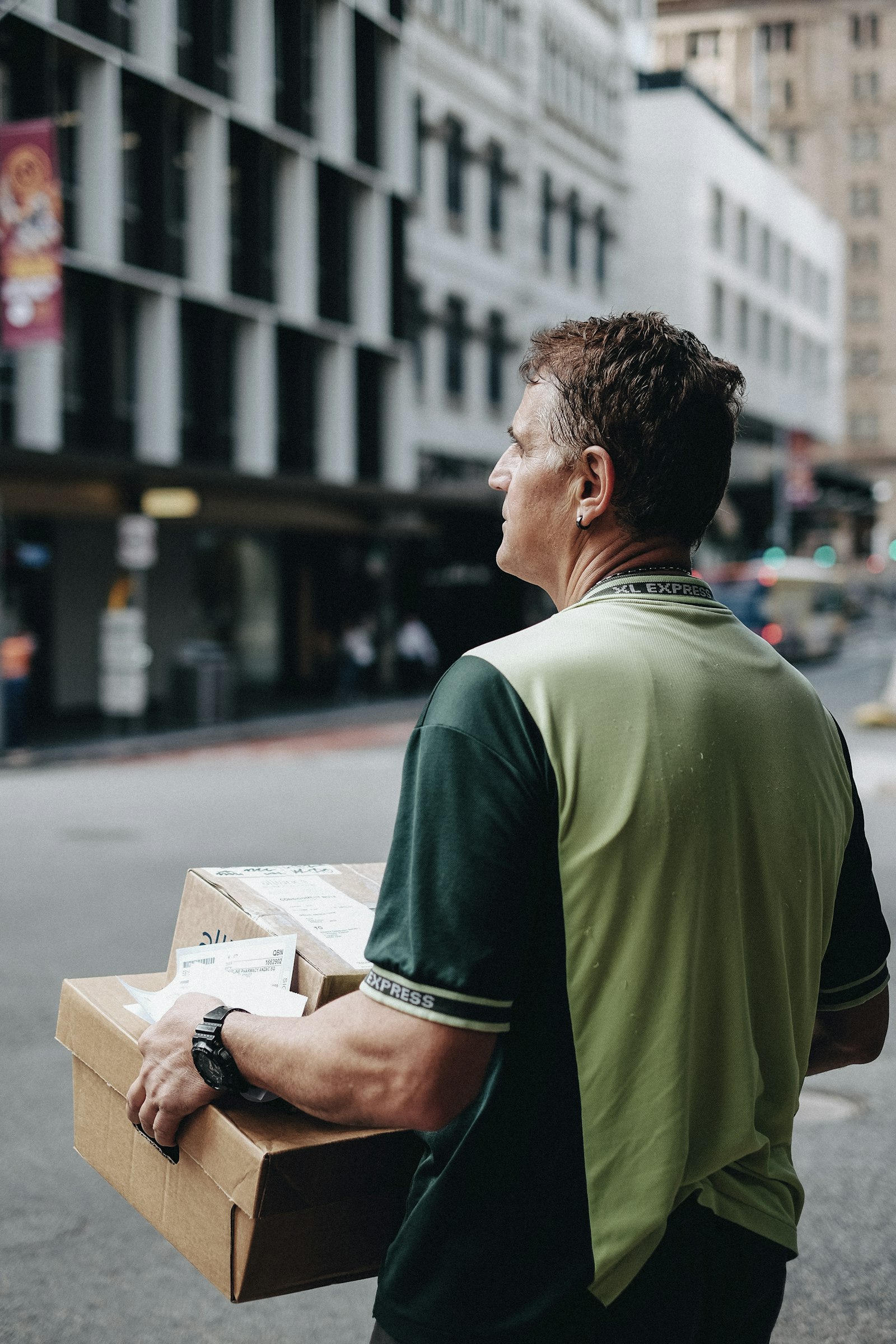 Folded printed shirts being counted and packed into a cardboard shipping box on a work table