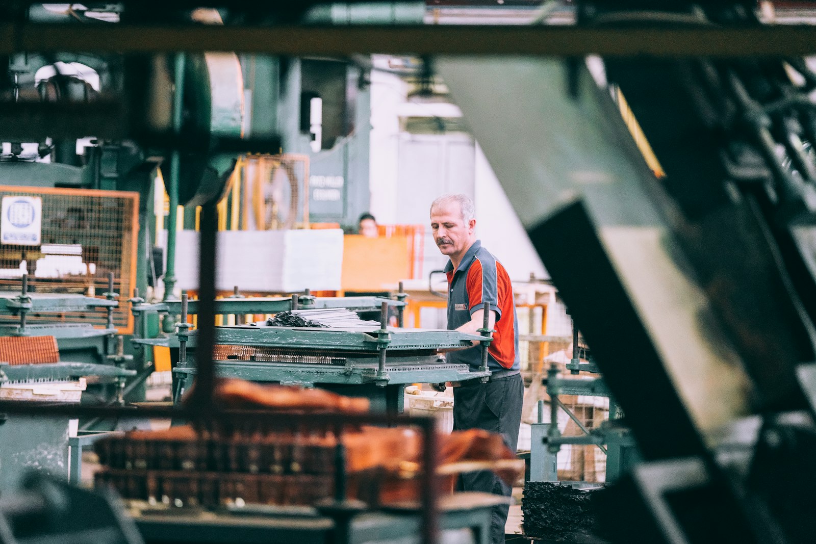 A shop worker at a press on the floor of a small printing workshop