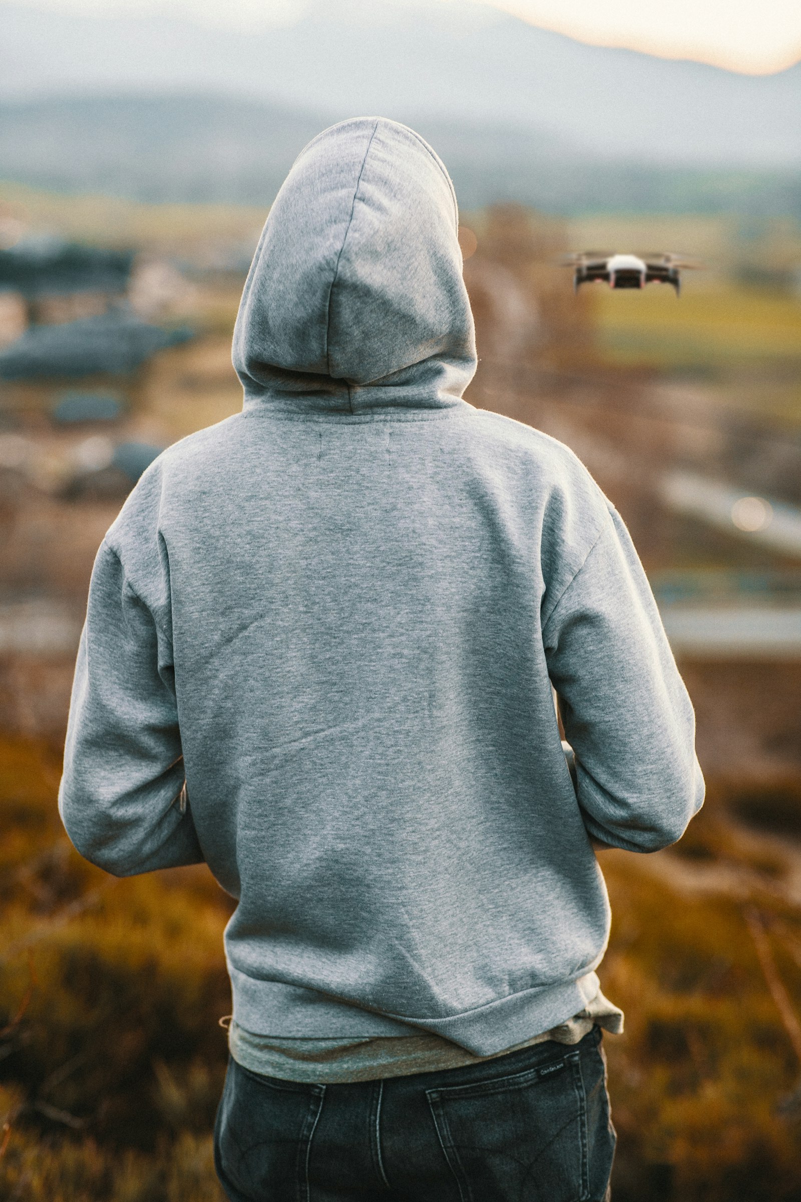 A person seen from behind wearing a grey pullover hoodie outdoors