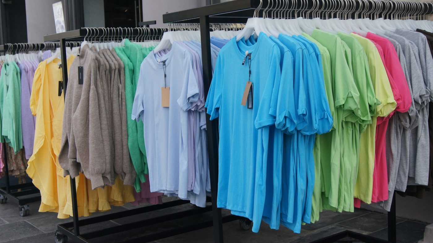 Rolling rails of plain t-shirts in pale blue, turquoise, lime, yellow, pink and grey with blank hang tags