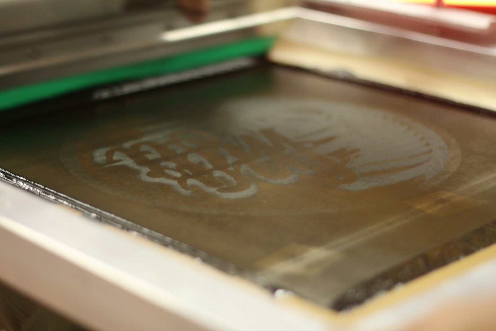 Close-up of a screen-printing screen in its frame, the stencilled design visible in the mesh